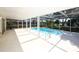 A screened in patio with a clean swimming pool, steel rails, and bright, white floors at 9816 Crofton Ln, Port Richey, FL 34668