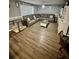 Cozy living room featuring wood-look flooring, a large sofa, and natural light at 10411 Summerview Cir, Riverview, FL 33578