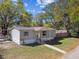 Single-story home with gray siding, a covered porch, and well-kept lawn surrounded by mature trees at 10501 Bay Hills Cir, Thonotosassa, FL 33592