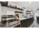 Modern kitchen with stainless steel appliances, granite counters, dark cabinets, and open shelving at 10501 Bay Hills Cir, Thonotosassa, FL 33592