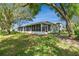 Back exterior showing a well manicured lawn and an enclosed, screened-in patio at 10716 Ashford Oaks Dr, Tampa, FL 33625