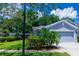 Exterior of a gray single-story home with a two-car garage, palm trees, and manicured landscaping at 10716 Ashford Oaks Dr, Tampa, FL 33625