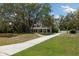Beautiful gray home with a long driveway surrounded by mature trees and lush greenery at 11207 Donneymoor Dr, Riverview, FL 33569