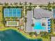 An aerial view showcases a community pool, tennis courts, and a picturesque pond surrounded by palm trees at 12817 Cobalt Ter, Bradenton, FL 34211