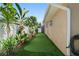 Side yard of the home with artificial putting green surrounded by tropical foliage at 13035 91St Ave, Seminole, FL 33776