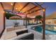 Inviting backyard pool with a shaded pergola, cozy seating, and festive string lights at 13035 91St Ave, Seminole, FL 33776