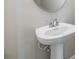 Close-up of a pedestal sink in the powder room with modern faucet and round mirror above at 13614 Stevenson Ln, Odessa, FL 33556