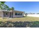 Green back yard featuring a screened lanai with a white door and a building exterior with multi-paned windows at 1400 63Rd S Ave, St Petersburg, FL 33705