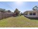 Green back yard featuring a wood fence, a mature shade tree, and a building exterior with windows at 1400 63Rd S Ave, St Petersburg, FL 33705