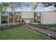 Striking front facade with floor-to-ceiling windows, a brick path, and manicured lawn at 14825 Lake Magdalene Cir, Tampa, FL 33613