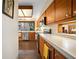 Kitchen featuring white countertops, stainless steel appliances, wood cabinets, and brick floors with window views of outdoor space at 14825 Lake Magdalene Cir, Tampa, FL 33613