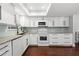 Bright kitchen features granite counters, white cabinets, modern appliances and hardwood flooring at 2033 Arbor Dr, Clearwater, FL 33760