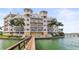 Stunning waterfront condo building with a private dock, balconies, and lush tropical landscaping at 205 Brightwater Dr # 101, Clearwater Beach, FL 33767