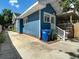 Exterior side view of blue house with driveway, trash cans, and stairs at 207 W Chelsea St, Tampa, FL 33603