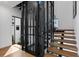 Modern staircase with wood treads and an elevator with black metal frame, offering a unique architectural feature at 2087 Michigan Ne Ave, St Petersburg, FL 33703