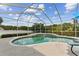 Inviting in-ground pool inside screened enclosure with a sun umbrella and lounge chairs at 2202 Colewood Ln, Dover, FL 33527