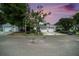 Exterior of the home with a two-car garage, mature landscaping, and a manicured lawn with dusk sky at 2456 Alhambra St, Clearwater, FL 33761