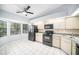 Functional kitchen with black appliances, cream cabinets, and a window above the sink at 2456 Alhambra St, Clearwater, FL 33761