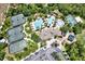 An aerial view of the community featuring a pool, splash pad, tennis courts, and a clubhouse surrounded by mature landscaping at 2614 Brookforest Dr, Wesley Chapel, FL 33544