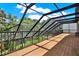 Spacious screened-in back porch with wooden floors and black metal supports and railings at 2614 Brookforest Dr, Wesley Chapel, FL 33544