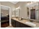 Bathroom with dual sinks, granite countertops, and dark wood cabinets, bedroom in background at 2614 Brookforest Dr, Wesley Chapel, FL 33544