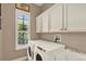 Well-equipped laundry room with modern washer and dryer, sink, and ample cabinet space at 2614 Brookforest Dr, Wesley Chapel, FL 33544