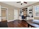Home office with built-in shelves, desk, hardwood floors, and view of bathroom at 2614 Brookforest Dr, Wesley Chapel, FL 33544