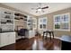 Home office with built-in shelving, desk, hardwood floors, and plantation shutters at 2614 Brookforest Dr, Wesley Chapel, FL 33544