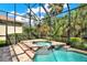 A relaxing in-ground spa pool surrounded by lush green landscaping and enclosed in a screened enclosure at 2614 Brookforest Dr, Wesley Chapel, FL 33544