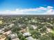 Overhead angle showing the green, tree-filled neighborhood with residential streets and nearby golf course under a partly cloudy sky at 2742 Sea Pines E Cir, Clearwater, FL 33761