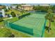 Aerial view of a community tennis court surrounded by manicured grass and palm trees at 2750 Reserve Ct # 101, Dunedin, FL 34698