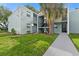 Two-story condo building with lush green lawn and mature palm tree on a sunny day at 2840 Somerset Park Dr # 203, Tampa, FL 33613