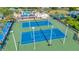 Aerial view showcasing well-maintained blue and green tennis courts surrounded by a secure fence at 30140 Barnaby Ln, Wesley Chapel, FL 33543