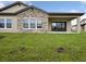 Exterior view of the home featuring a lush green lawn and covered patio with sliding glass doors at 35609 Stableton Lane, Zephyrhills, FL 33541