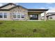 A shot of the backyard with a covered porch, stone exterior accents, and sliding glass doors at 35609 Stableton Lane, Zephyrhills, FL 33541