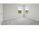 Empty bedroom with carpet flooring, white walls, and natural light streaming in through the windows at 35609 Stableton Lane, Zephyrhills, FL 33541
