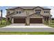 Modern townhome exterior with stone accents, dark garage doors, and well-maintained landscaping at 35609 Stableton Lane, Zephyrhills, FL 33541