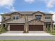 Beautiful townhouse showcasing a stone facade and two-car garage, offering a modern and stylish curb appeal at 35609 Stableton Lane, Zephyrhills, FL 33541