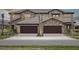 Beautiful front exterior of townhomes, showcasing the stone facade, tandem garages, and well-manicured lawns at 35609 Stableton Lane, Zephyrhills, FL 33541