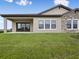 An exterior view of a back patio with stone accents, lush greenery, and a sliding door at 35617 Stableton Lane, Zephyrhills, FL 33541