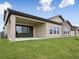 An exterior view of a back patio with stone accents, lush greenery, and a sliding door at 35617 Stableton Lane, Zephyrhills, FL 33541