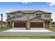 New townhome exterior featuring stone accents, a tile roof, and individual driveways leading to spacious two-car garages at 35617 Stableton Lane, Zephyrhills, FL 33541