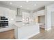 Well-lit kitchen features white cabinets, a center island with sink, and stainless steel appliances at 35617 Stableton Lane, Zephyrhills, FL 33541