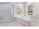 Bright bathroom featuring a marble encased tub, walk-in shower, and double windows for natural light at 3610 Woodbridge Ave, North Port, FL 34287