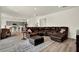 Spacious living room with dark brown leather sectional and view into the kitchen at 3952 Almond Brook Blvd, Land O Lakes, FL 34638