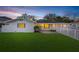 Charming single-story home featuring a well-manicured lawn and a classic white picket fence at dusk at 4709 W Fair Oaks Ave, Tampa, FL 33611