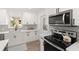 Close-up of kitchen showing stainless steel appliances, gray backsplash, white cabinets and quartz countertops at 4709 W Fair Oaks Ave, Tampa, FL 33611