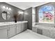 Bathroom featuring dual sinks, grey cabinets and a jacuzzi tub with a view at 5405 El Cerro Dr, New Port Richey, FL 34655