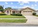 Charming single-story home with a well-maintained lawn, solar panels and a two-car garage under a blue sky at 5405 El Cerro Dr, New Port Richey, FL 34655