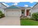 Inviting single-Gathering home with a two-car garage, complemented by manicured landscaping and a colorful front door at 5492 Summer Sunset Dr, Apollo Beach, FL 33572